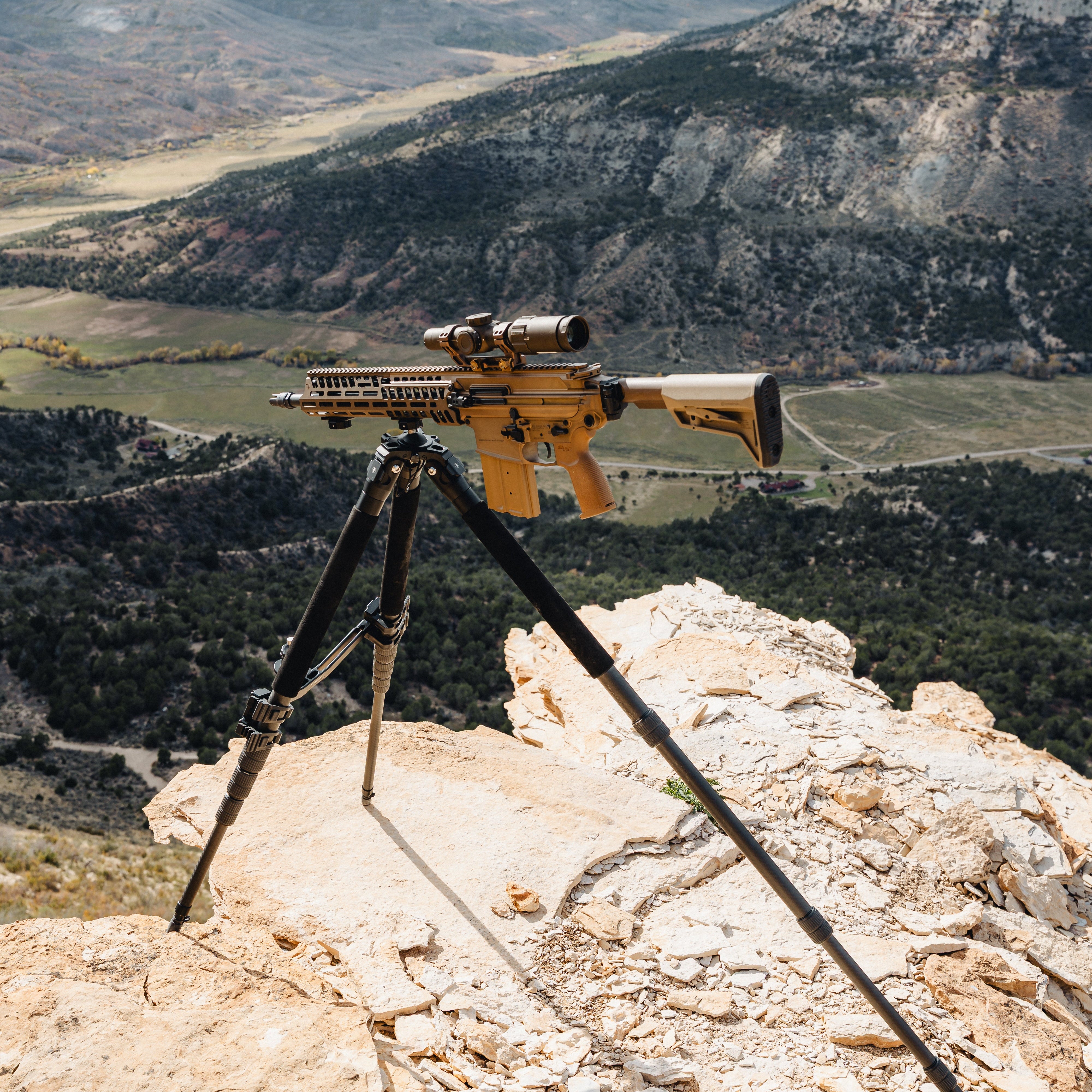 Riflescope on a tripod with a mountainous landscape in the background