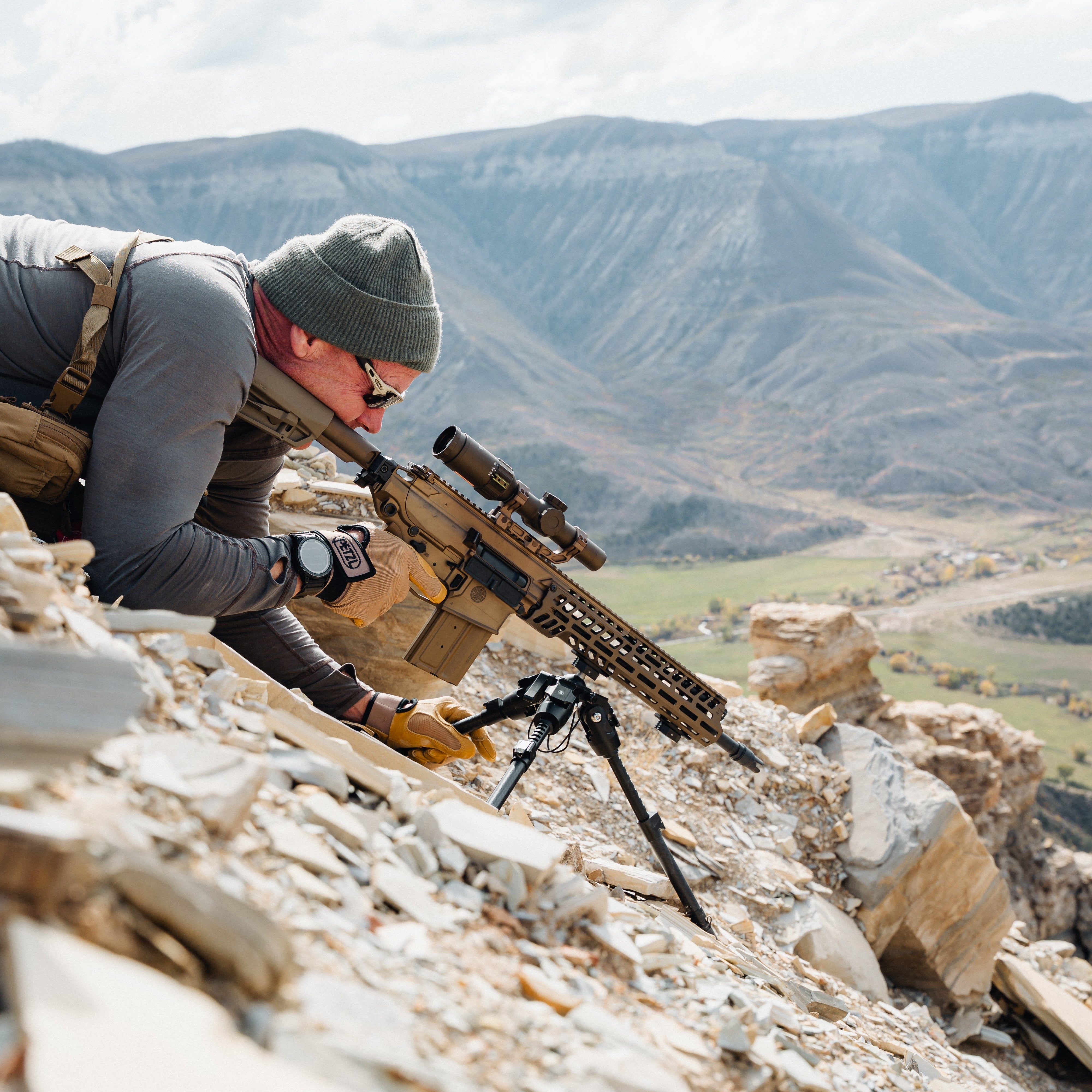 Person with a rifle on a rocky mountain landscape